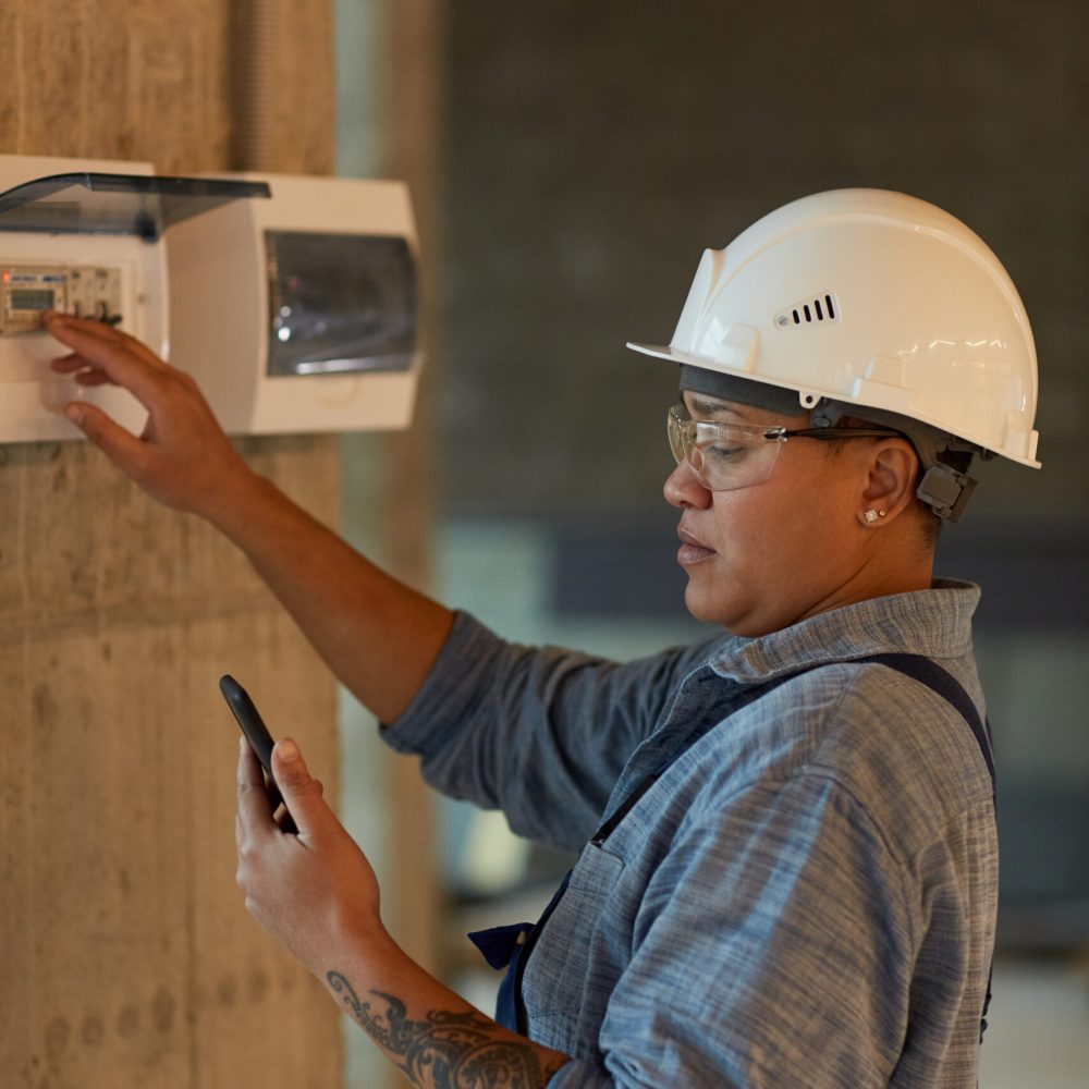 Female Electrician Inspecting Switchboard